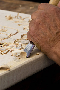 用凿子雕刻木头的工匠的手特写图片