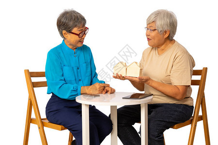 高级销售妇女向白背景的退休老年客户提供住房模式图片