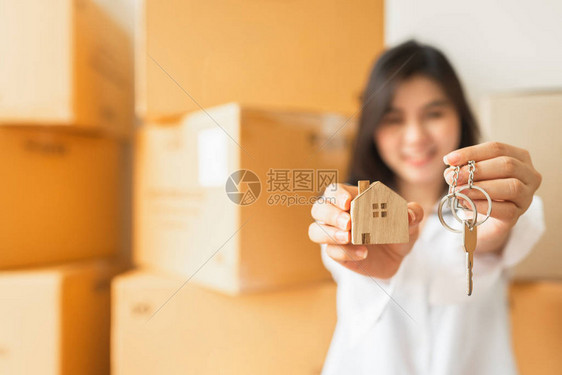 笑着的亚洲妇女紧贴地拿着钥匙和木屋模型图片