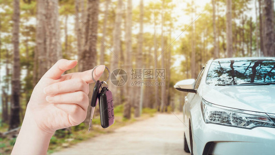 手持钥匙或使用电话支持在线申请租车或保险在新常态业务中以软焦点现代紧凑型汽车在图片