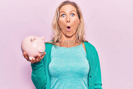 中年的caucasian金发女人拿着小猪银行吓着并图片