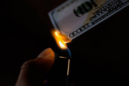 燃烧的美元和手中的打火机特写图片