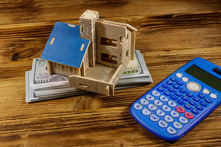 房屋模型美国一百美元钞票和木制背景上的计算器物业投资房屋贷款房屋抵押图片