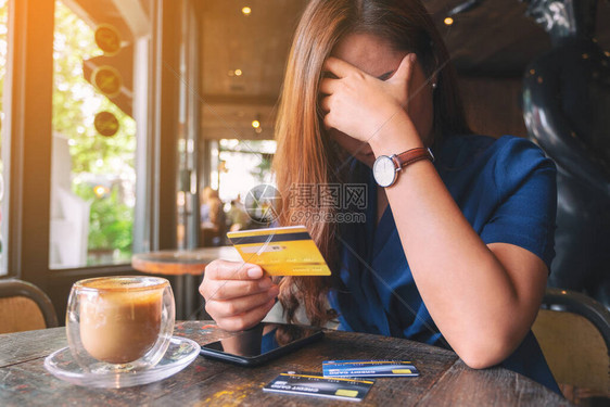 一个亚裔女在持有信用卡时紧张和破碎图片
