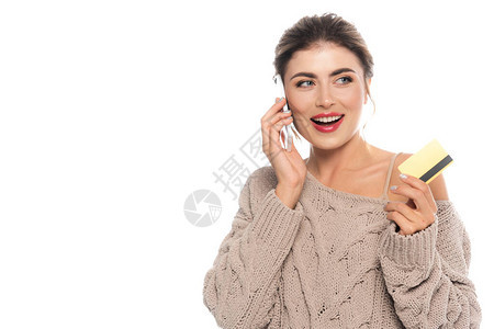 穿着编织毛衣的欢乐女人在用智能手机说话的同时持有孤立在白图片