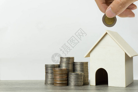 存钱住房贷款抵押贷款未来概念的房地产投资一只手把硬币放在白色背景和空间上的小住宅和钱袋上一项图片