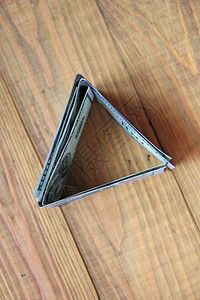 木板上的一百美元纸币百元钞票折叠成三角形现金以三角形的式站在木质背景图片