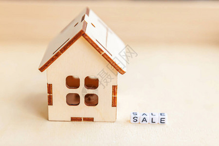 木制背景上刻有销售字母的微型玩具模型屋生态村抽象环境背景房地产抵押财产保险甜蜜家园图片