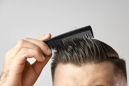 特写年轻人用塑料梳子理头发理发店后的造型头发保健失图片