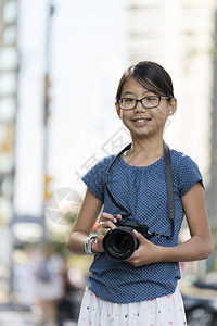 带数码摄影机的年轻小女孩摄影师在户外图片