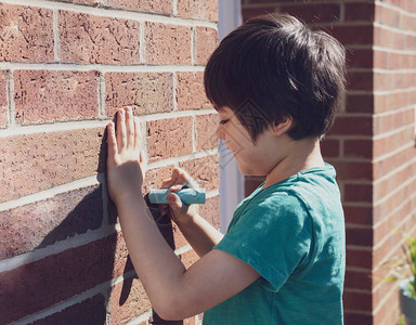 用粉笔在砖墙上写字的孩子图片