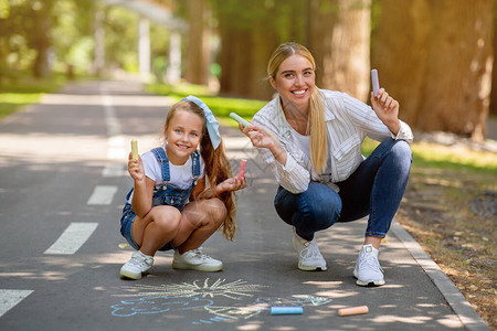 快乐的妈和女儿在公园外门边画彩色粉丝图片