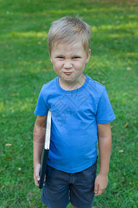 一个小男孩在公园站立手里拿着一本书他皱着鼻子图片