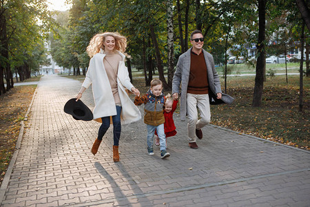 家庭爸妈儿子和女儿正在公园里的人行道小巷里奔跑图片