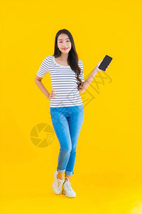 肖像美丽的亚洲年轻女微笑快乐地使用黄色孤立背图片