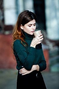 年轻时尚的女人在城市街道上喝茶时髦的欧洲女孩在街上拿着铁纸玻璃华丽的年轻女子图片