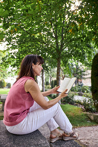 在公园里看书的女人坐在石头图片