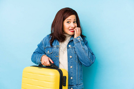 Middlr年龄Latin旅行家女人拿着手提箱孤立的咬指甲背景图片