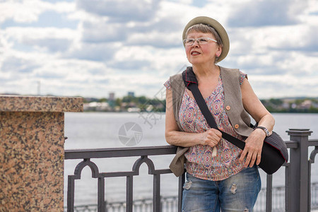一个快乐的老妇人夏天沿着城市走图片