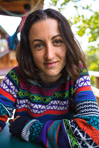 一个穿着毛衣的女人坐在农村木屋的门廊上阳台上一个微笑图片
