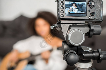 在客厅数码摄影机旁边演奏声吉他的女孩的牙套中被选为图片