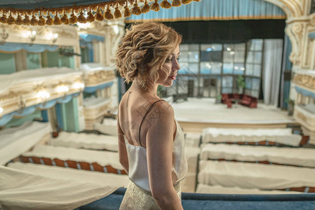 一个穿着独身衣服的美女在古典空旷剧院的阳台上看图片