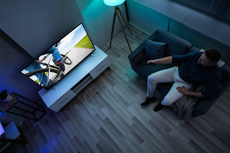 在家躺在沙发上看电视的男人图片