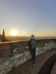 孩子在日落时仰靠布雷西亚城堡塔楼的图片