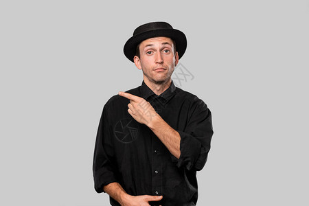一个穿黑衬衫和猪肉派帽的时髦帅哥的肖像指着灰色背景隔图片