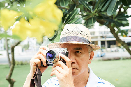 身戴草帽的亚洲老人在夏季公园散步图片