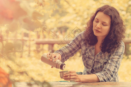 旅行的女人从热水瓶里倒茶图片