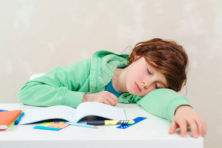 疲倦的小学生在做作业时睡在桌子旁困难教育家庭作业概念男孩做作业压力大又累的孩子沮丧的孩子坐在办公桌图片