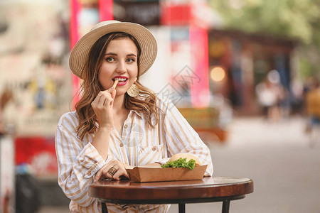 美丽的年轻女子在户外吃美味图片