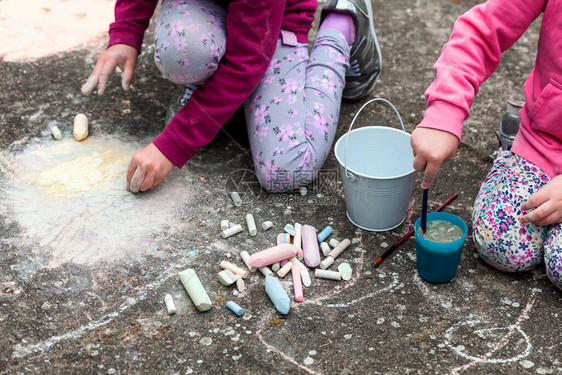 孩子们用粉笔在坐地上的混凝土上画图片