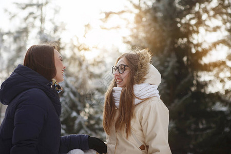 两个穿长发围巾和夹克的年轻美女在雪林户外聊天很愉快青春美丽健康的生活方式梦图片