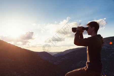 山的年轻人通过双筒望远镜与峡谷视图带有复制空间的横幅旅行和发现冒险和自由图片