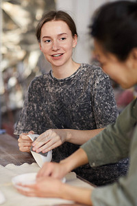 穿着临时短袖运动衫的年轻女手工艺人坐在办公桌边图片