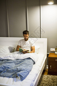 英俊的年轻人在床上看书图片