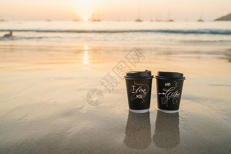 两杯一次黑纸站在日落时海边沙滩上情人节的浪漫概念校对图片
