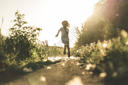 一个小男孩在日落时分沿着马路奔跑图片