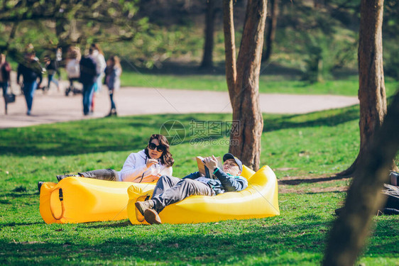 一对夫妇躺在城市公园的黄色充气床垫上图片