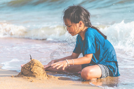 小女孩在芭堤雅海滩玩海浪和沙子图片