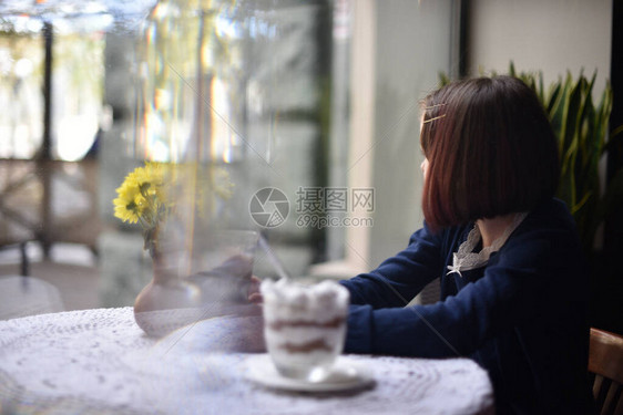 小女孩在咖啡馆里喝热巧克力女学生在咖啡馆里喝可女孩在咖啡馆下课后喝可图片