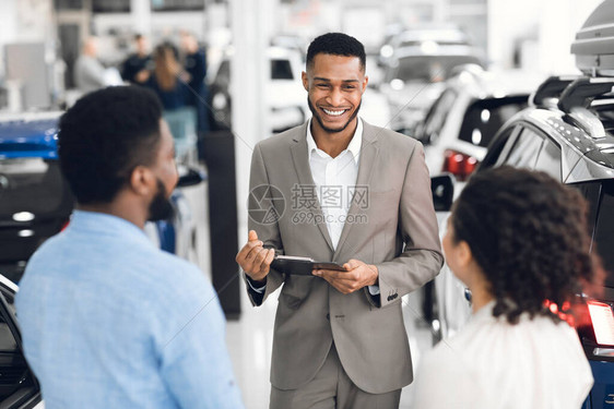 汽车销售专业经销商与在豪华经销店展示汽车的客户交谈图片