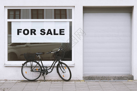 待售标志在商店橱窗外停放自行车图片