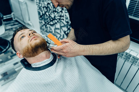 理发师在理发店用剃须机修剪胡须发型设计过程理发师剃胡子男胡图片