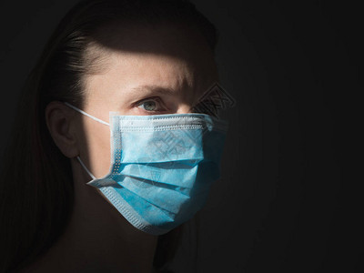 一个女人戴上医用一次面罩以避免传染图片