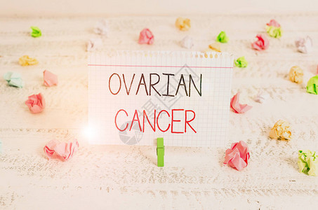 显示卵巢癌的书写笔记在卵巢组织中形成的任何癌生长的商业概念绿色衣夹白色木背景背景图片
