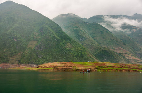 大宁河上的龙门峡谷景观与多座高大的绿色山脉在朦胧的cloudscape在翡翠绿水岸边的一图片