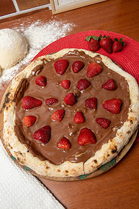 木桌上的巧克力披萨和草莓图片